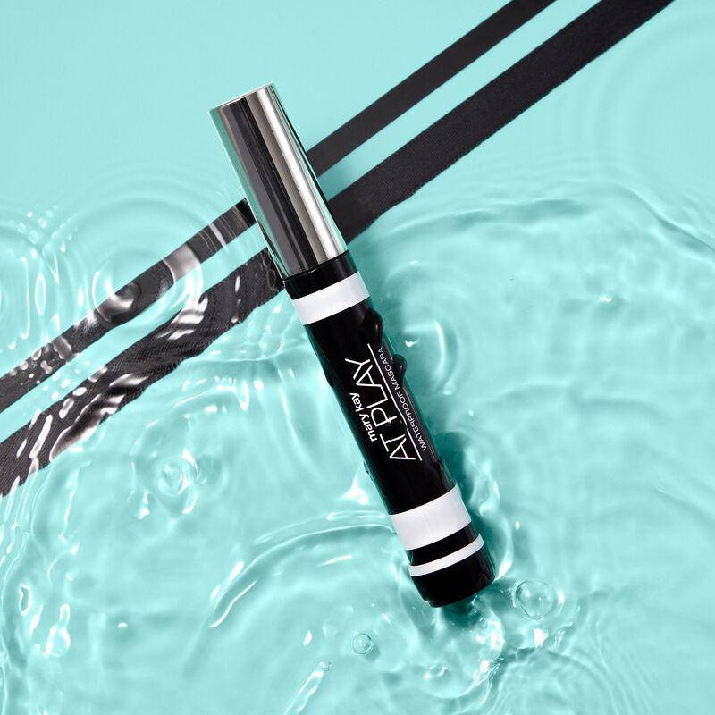 Closed tube of Mary Kay At Play Waterproof Mascara in water with two diagonal black stripes in the background image number null