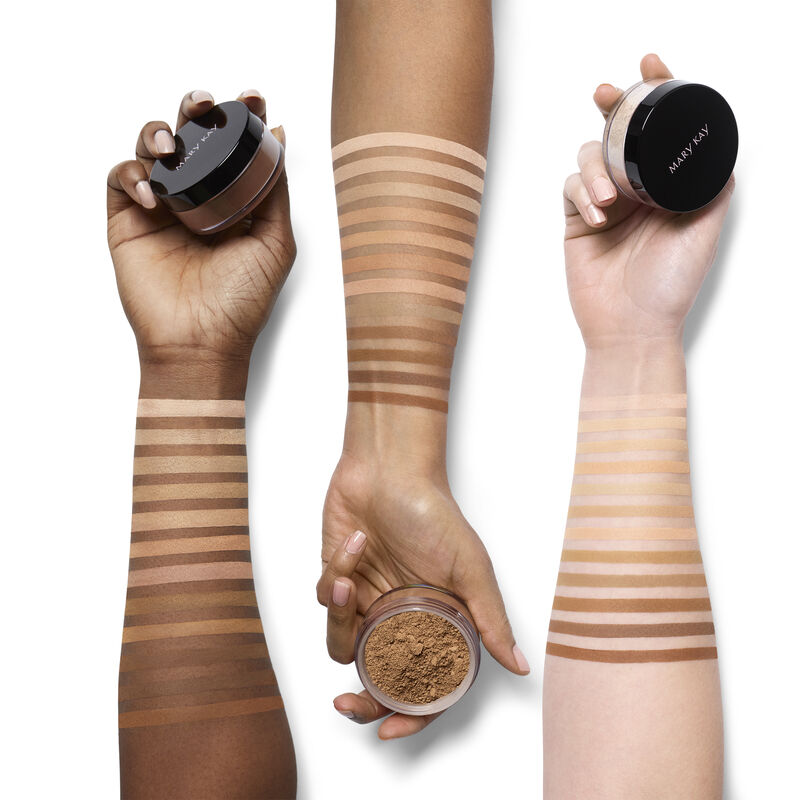 An ivory, beige and bronze arm with shade swatches of all of the Mary Kay Silky Setting Powder shades with hands holding product containers. image number null