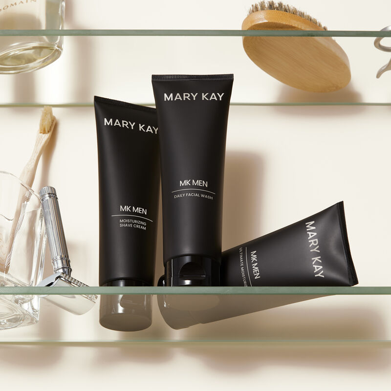 MKMen Moisturizing Shave Cream, MKMen Daily Facial Wash and MKMen Ultimate Moisturizer on a shelf next to a razor, men&rsquo;s brush and other toiletries
