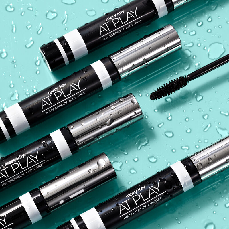 Five tubes of Mary Kay At Play Waterproof Mascara and accompanying wand surrounded by water droplets image number null