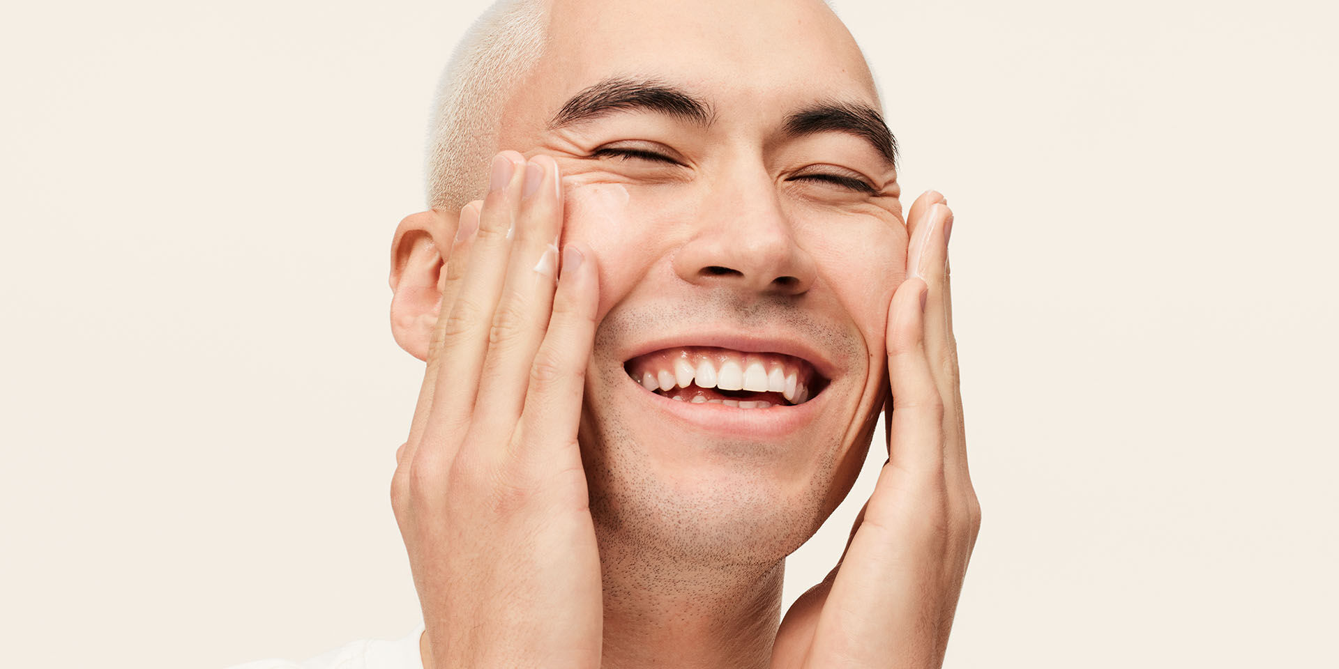 Modelo masculino sonriendo y aplicando la Loci&oacute;n Facial Hidratante Intensiva MKMen&reg; en el rostro