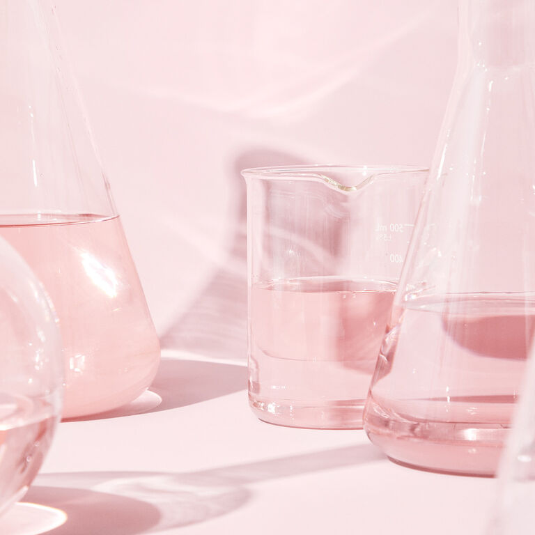 Vasos de vidrio de laboratorio sobre un fondo rosa. 