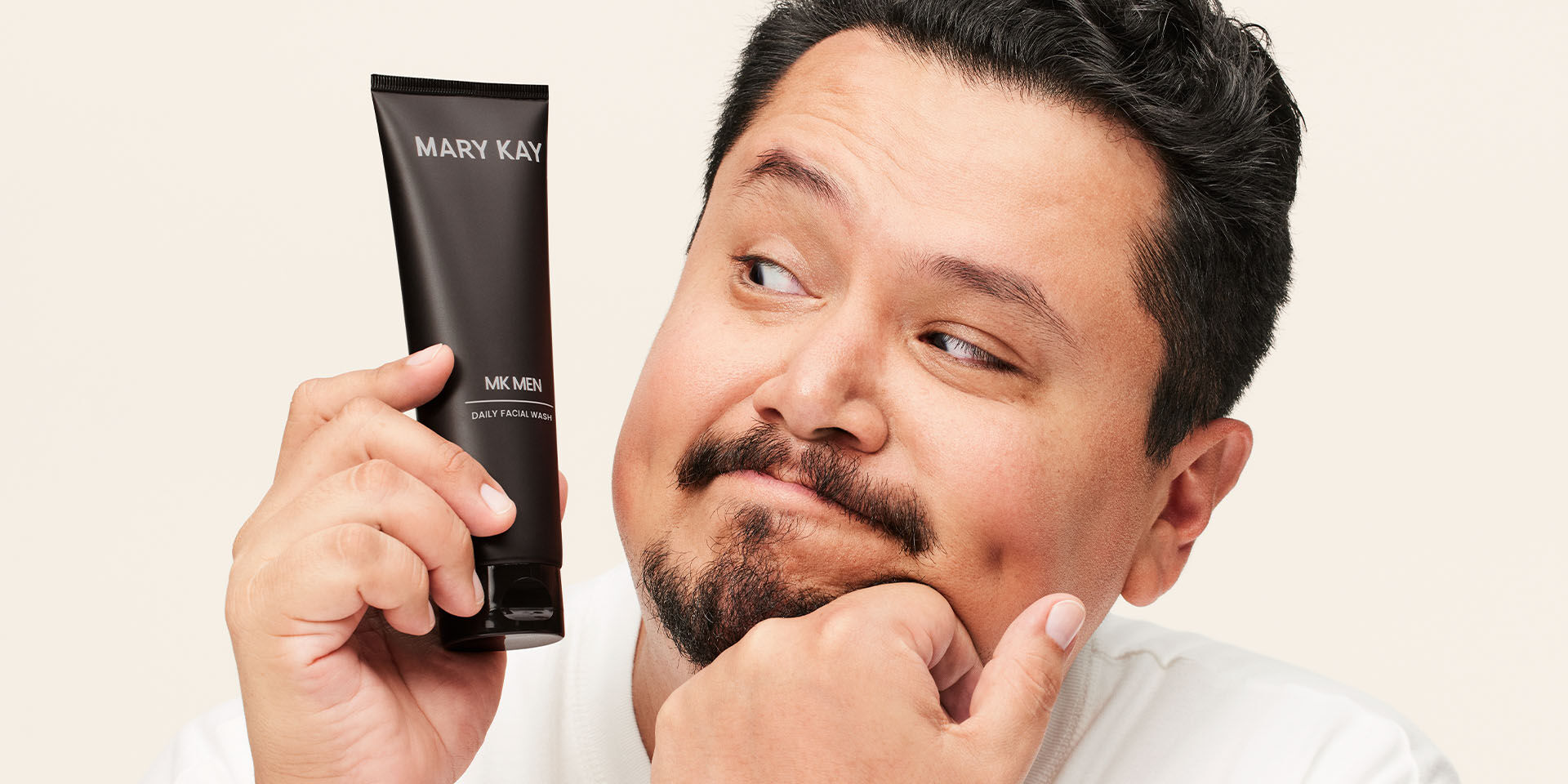 Modelo masculino sosteniendo el tubo del Gel Limpiador Facial MKMen&reg; junto a su rostro