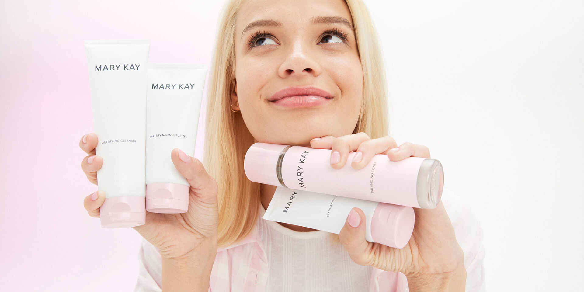 Modelo rubia sosteniendo los cuatro productos de la l&iacute;nea de cuidado facial de Mary Kay&reg;