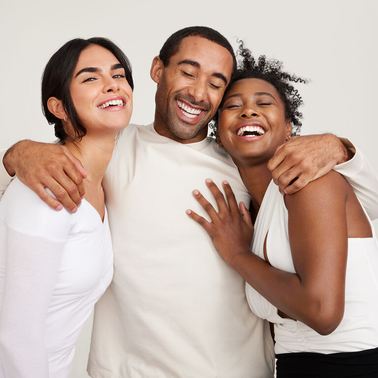 Un grupo de dos mujeres y un hombre ri&eacute;ndose y abraz&aacute;ndose todos  